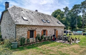 A stone house with a sloped roof, wooden shutters, and a small porch area. - Maison avec piscine et jaccuzz (Saint-Jal)