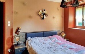 A bedroom with a bed, a nightstand, a wall clock, and a window with curtains. - Maison avec piscine et jaccuzz (Saint-Jal)
