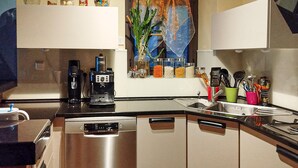 Eine moderne Küche mit Geschirrspüler, Kaffeemaschine und verschiedenen Gläsern auf der Arbeitsfläche.