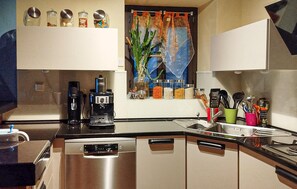 Eine moderne Küche mit Geschirrspüler, Kaffeemaschine und verschiedenen Gläsern auf der Arbeitsfläche.
