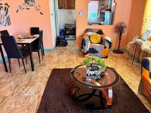 A living room with a sofa, a coffee table with a plant, and a dining area with chairs and a table. - Mammee Bay Hideaway (St. Ann Parish)