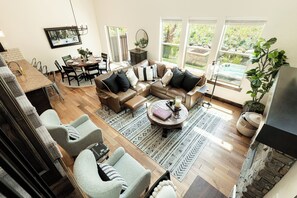 Un salon spacieux avec un grand canapé, un coin repas et une vue sur un jardin grâce à de grandes fenêtres.