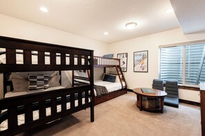 A room with bunk beds, a small round table, and a window with blinds. - Private Backyard & Hot Tub | Minutes to Deer Valley, Jordanelle & Park City (Kamas)