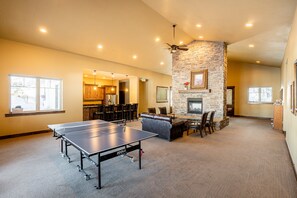 A spacious indoor area with a ping pong table, a stone fireplace, and a seating area with a sofa and chairs. - Private Backyard & Hot Tub | Minutes to Deer Valley, Jordanelle & Park City (Kamas)