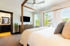 Une chambre dotée d’un grand lit, d’un ventilateur de plafond, d’une télévision et offrant une vue sur l’extérieur.