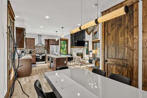 A modern kitchen with a large island, built-in appliances, and a stone fireplace. - Vintage Vale at Eagles Nest - Views, yard games, hot tub, outdoor fireplace (Elk Park)