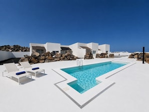 A modern outdoor pool area with lounge chairs and a clear blue sky. - Standard Suite · 2 bedrooms Adults Only (Costa Teguise)