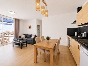 Un espai de vida modern amb zona de menjador, cuina i vistes a l'exterior.