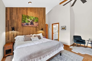 Ein Schlafzimmer mit einem großen Bett, einer Holzwandverkleidung, einem Bild eines Elchs, einem Spiegel und einem Stuhl.