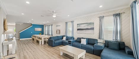 A spacious living area with a sectional sofa, a coffee table, and a dining table.