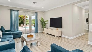Una sala de estar con televisor de pantalla plana, una mesa de centro y un sofá.