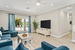 A living room with a flat-screen TV, a coffee table, and a sofa. - Legends Coastal Cottage, Arcade, Golf simulator, Near Disney (Kissimmee)