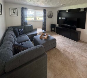 Ein Wohnzimmer mit Ecksofa, Flachbildfernseher und Kamin.
