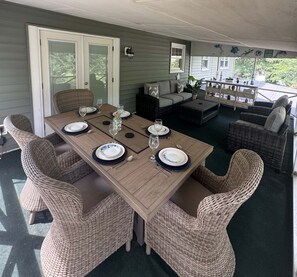 A covered outdoor dining area with a wooden table set for four, surrounded by wicker chairs. - Welcome to Getaway on the Bay | Your Waterfront Annapolis Escape (Annapolis)