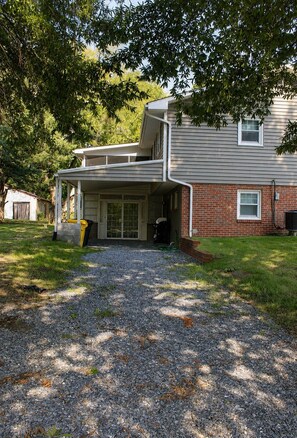 A two-story house with a covered porch, a brick exterior, and a gravel driveway. - Welcome to Getaway on the Bay | Your Waterfront Annapolis Escape (Annapolis)