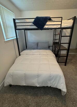 A bunk bed with a white mattress and a blue blanket on the top bunk.