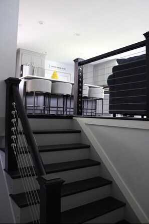 A staircase with black railings leading to a kitchen area with white cabinets and a yellow decorative item. - Welcome to Getaway on the Bay | Your Waterfront Annapolis Escape (Annapolis)