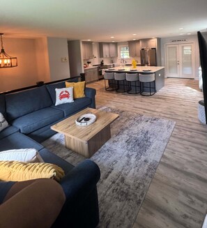 A modern living room with a sofa, coffee table, and a kitchen area in the background. - Welcome to Getaway on the Bay | Your Waterfront Annapolis Escape (Annapolis)