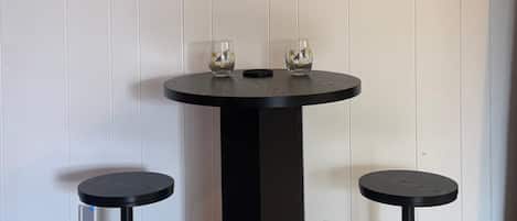 A black round table with two stools, a wall clock, and a power outlet.