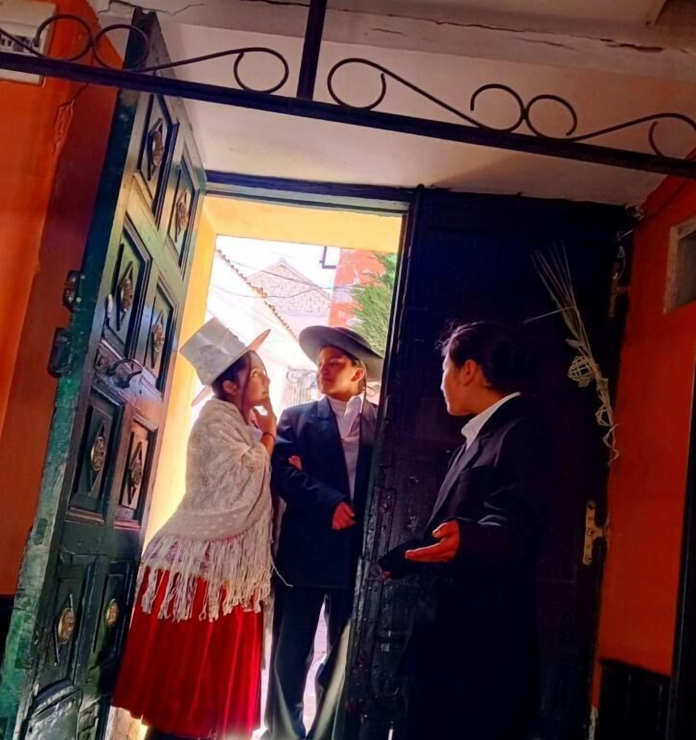 Un vano con barandilla metálica decorativa, una puerta verde de diseño tradicional y una pared roja.