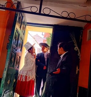 A doorway with a decorative metal railing, a green door with a traditional design, and a red wall.