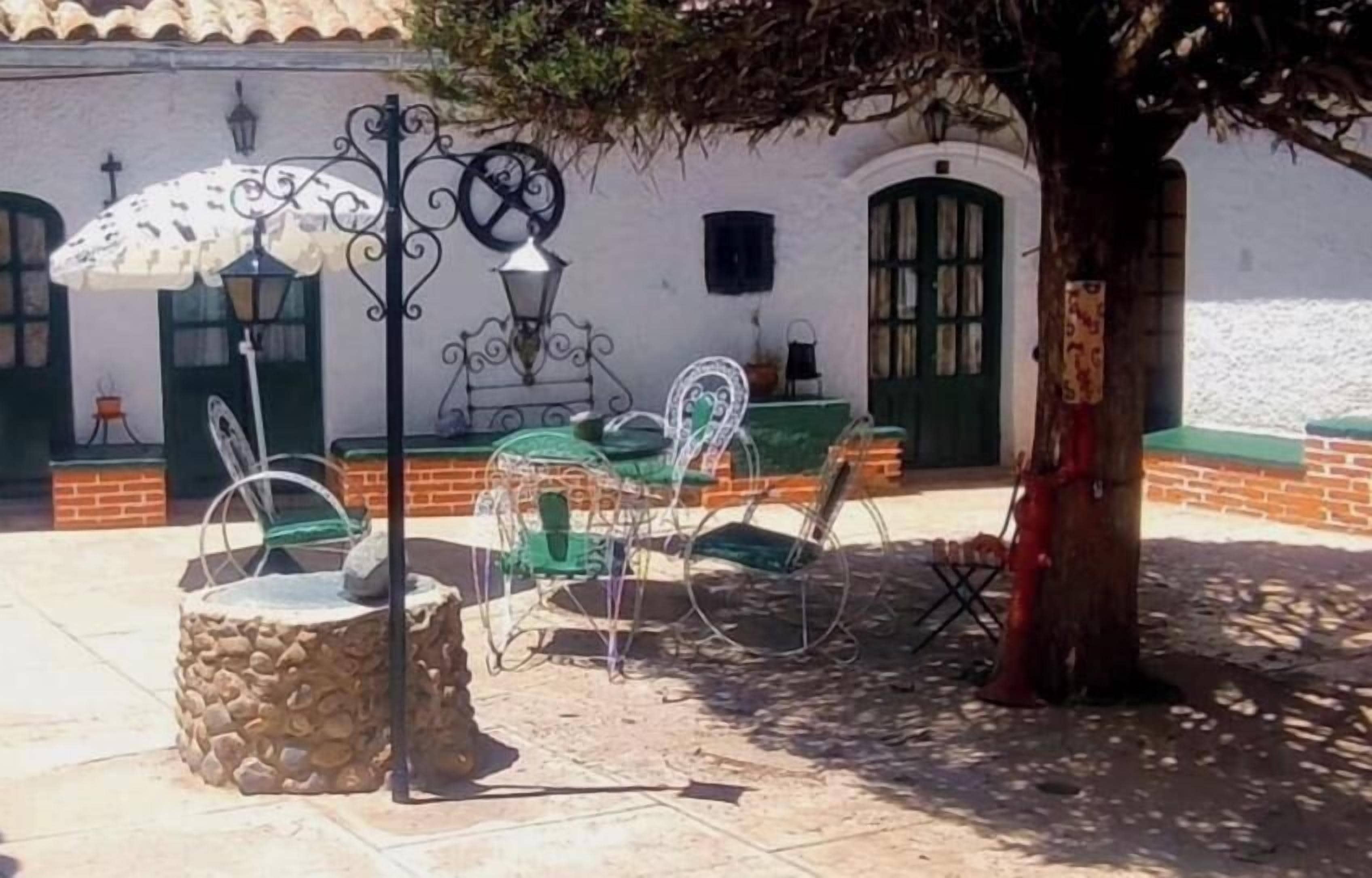 Mobiliario exterior con sillas metálicas y una mesa, una maceta de piedra y un árbol.