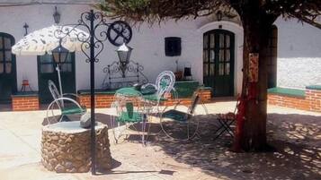 Mobiliario exterior con sillas metálicas y una mesa, una maceta de piedra y un árbol.