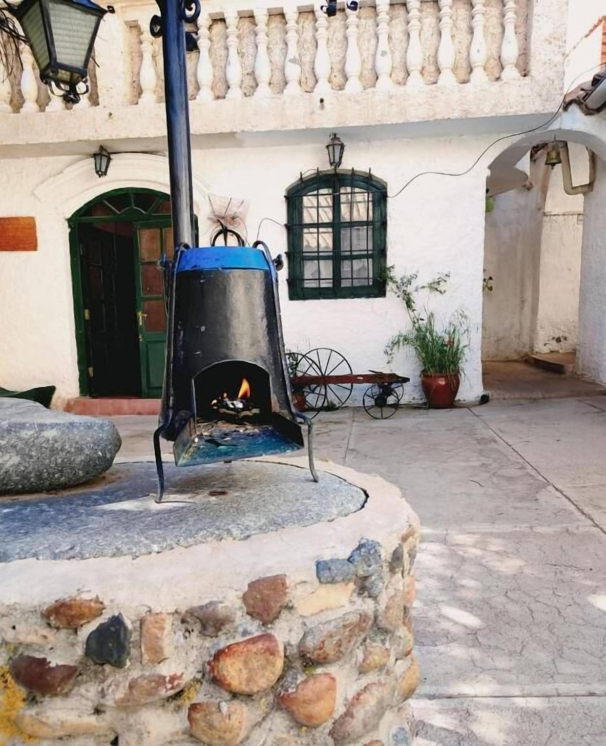 Un área de estar al aire libre con piedras, un hogar, una mesa de metal y una planta en maceta.