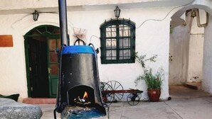 A stone outdoor seating area with a fire pit, a metal table, and a potted plant.