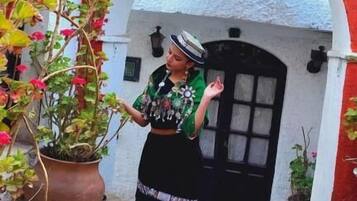 Una persona de pie frente a un edificio con puerta negra y un arco.