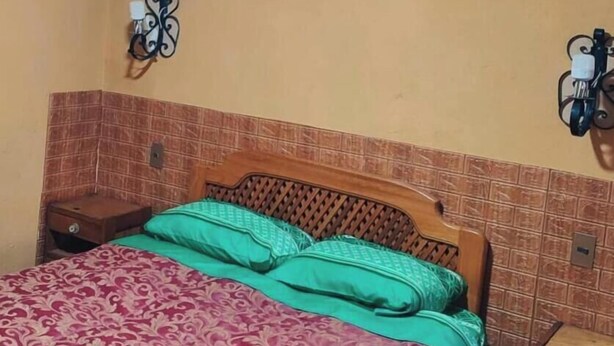A room with a bed, two wall-mounted lamps, and a picture on the wall.