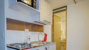 A compact kitchen with a gas stove, a microwave, and a sink. - Coliving Majestic (Manizales)