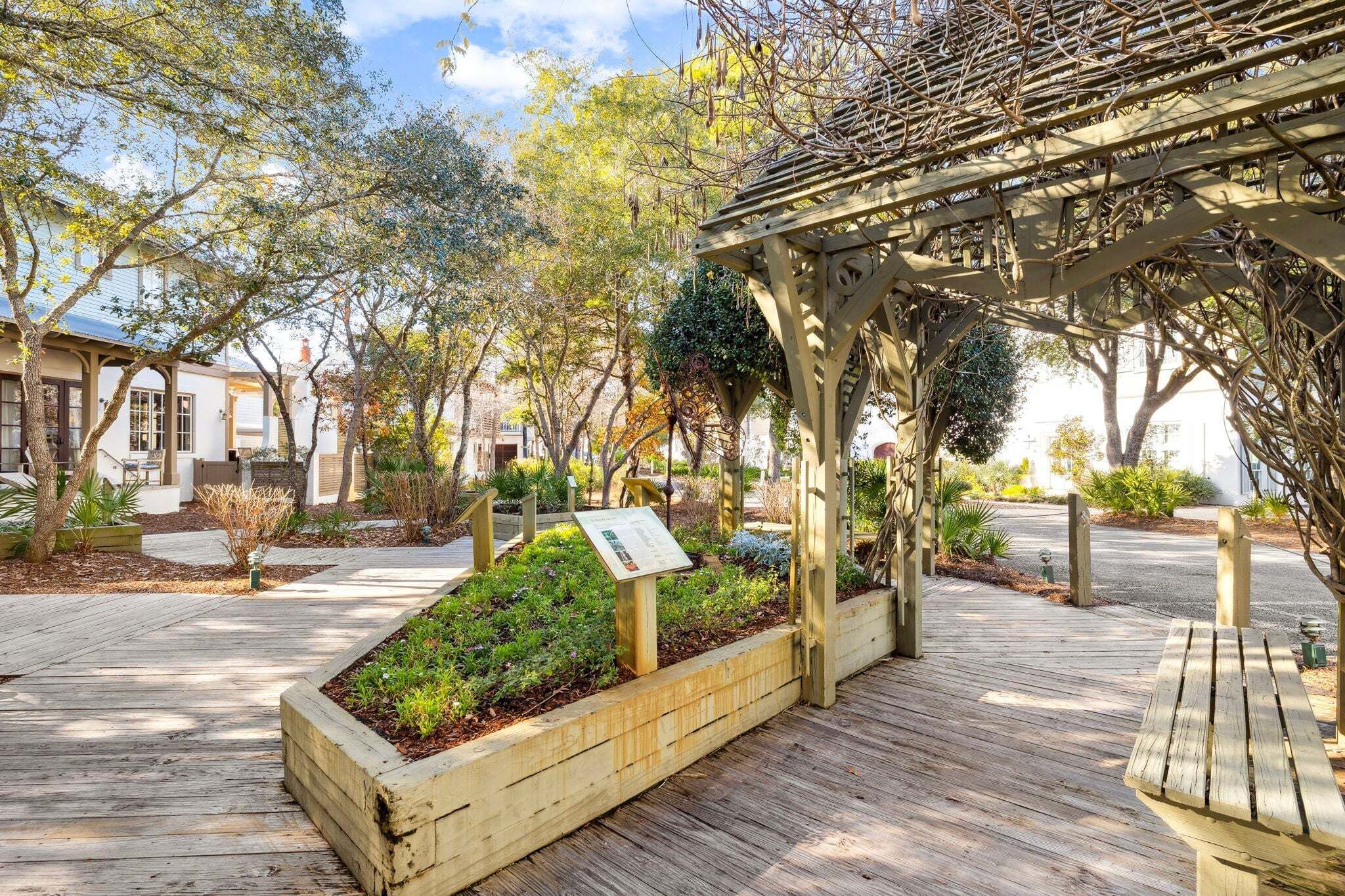 Eine Holzterrasse mit Pflanzkübeln, einer Pergola und einer Bank.