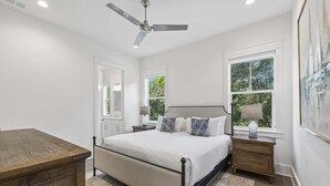 A bedroom with a bed, bedside tables, a ceiling fan, and a window with a view of greenery. - Easy Walk 2 Beach! Private Pool, LSV/Golf Cart & Bikes! (Santa Rosa Beach)