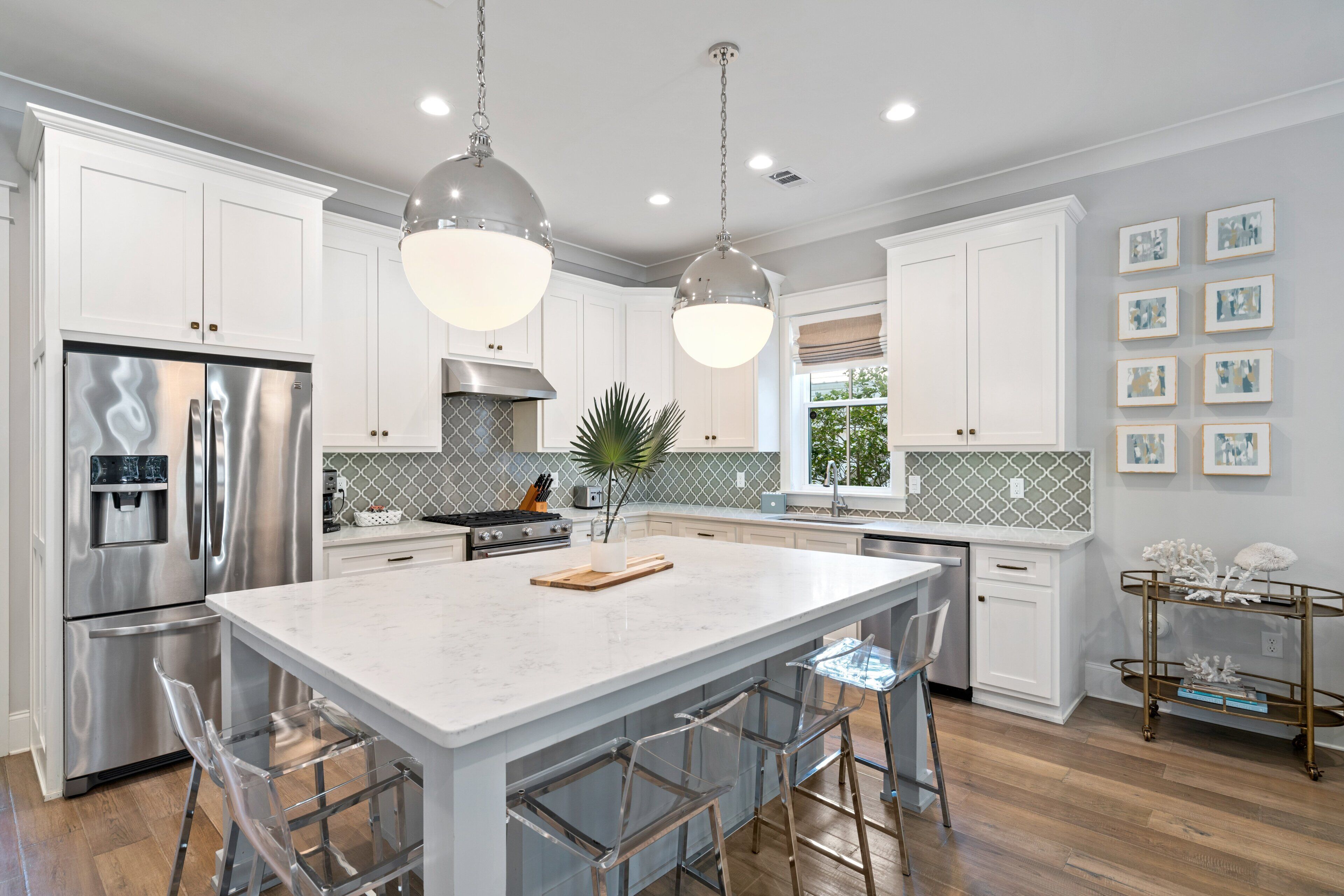 A modern kitchen with stainless steel appliances, a marble island, and pendant lighting.