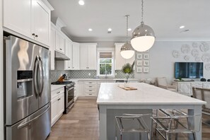 A modern kitchen with stainless steel appliances, a marble island, and pendant lighting. - NEW! EZ Walk to Beach! Private Pool, LSV/Golf Cart, & Bikes! (Santa Rosa Beach)