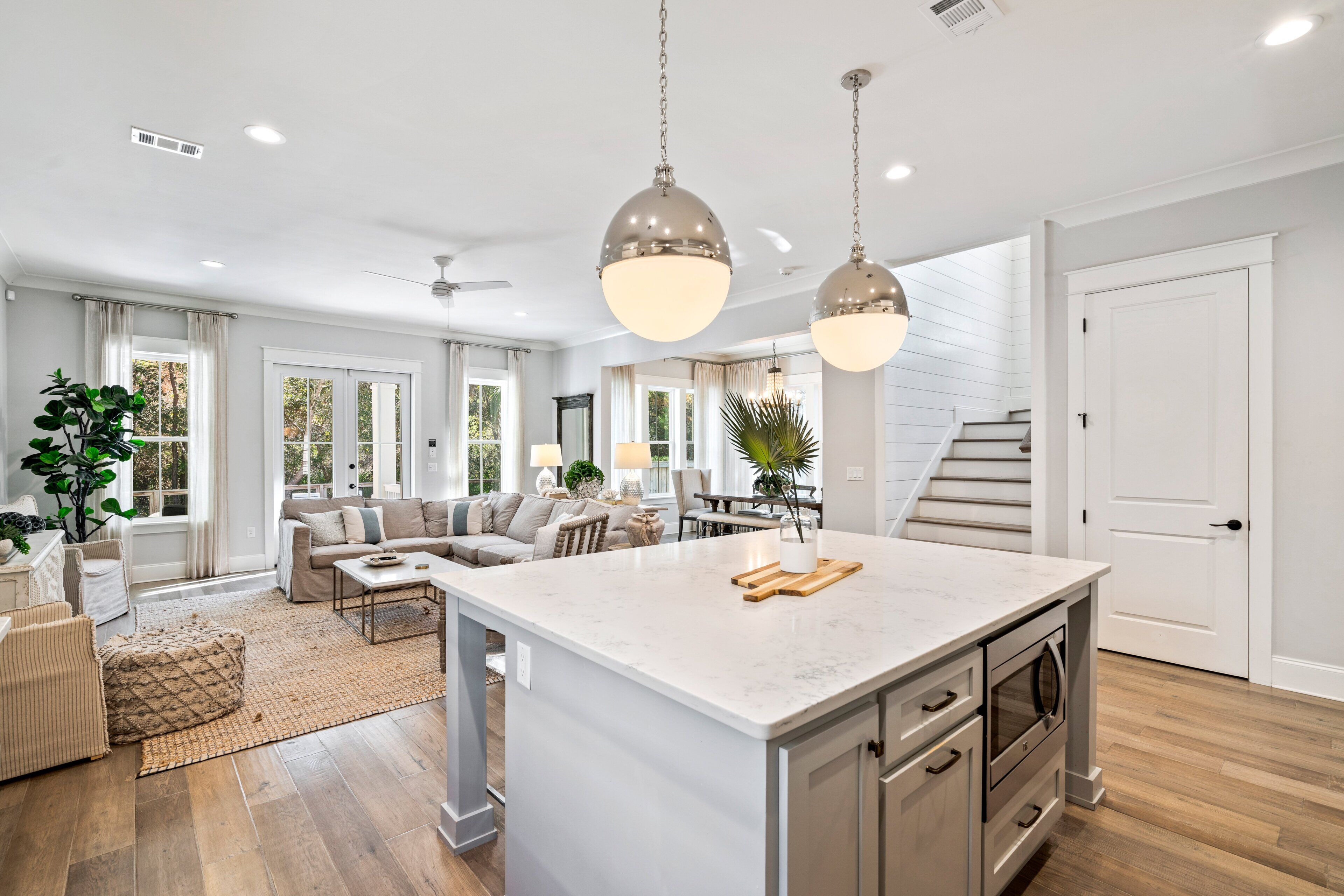 A spacious kitchen with a large island, wooden flooring, and pendant lighting.
