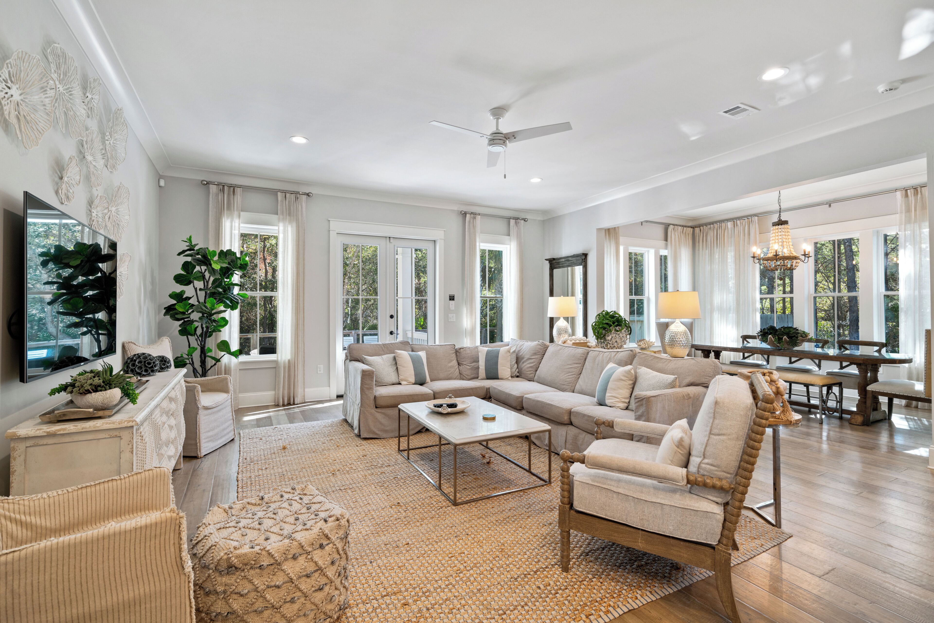 A spacious living room with a sectional sofa, a coffee table, and a dining area with a chandelier.