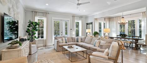 A spacious living room with a sectional sofa, a coffee table, and a dining area with a chandelier.