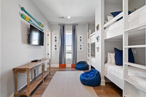 Quarto moderno com beliches, televisão de tela plana e um banco de madeira.