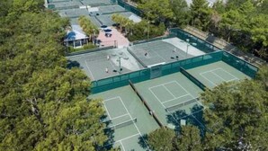 Luftaufnahme eines Tennisplatzkomplexes, umgeben von dichtem Wald.