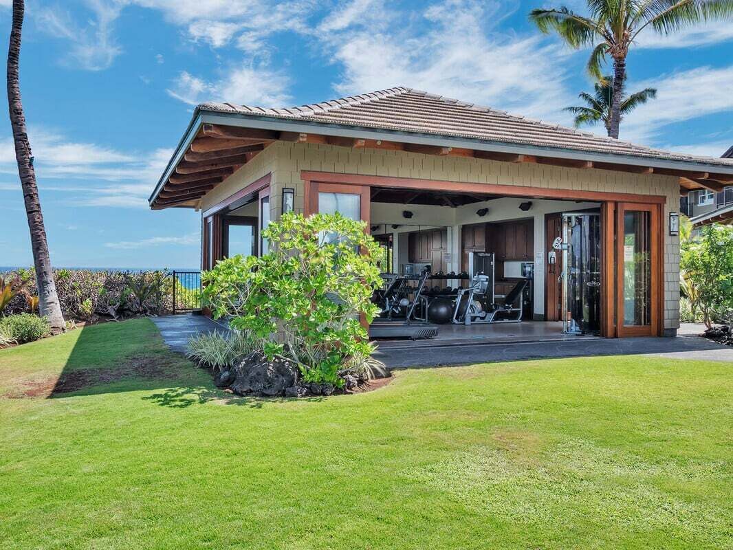 A modern house with a covered outdoor area, exercise equipment, and a well-maintained lawn.