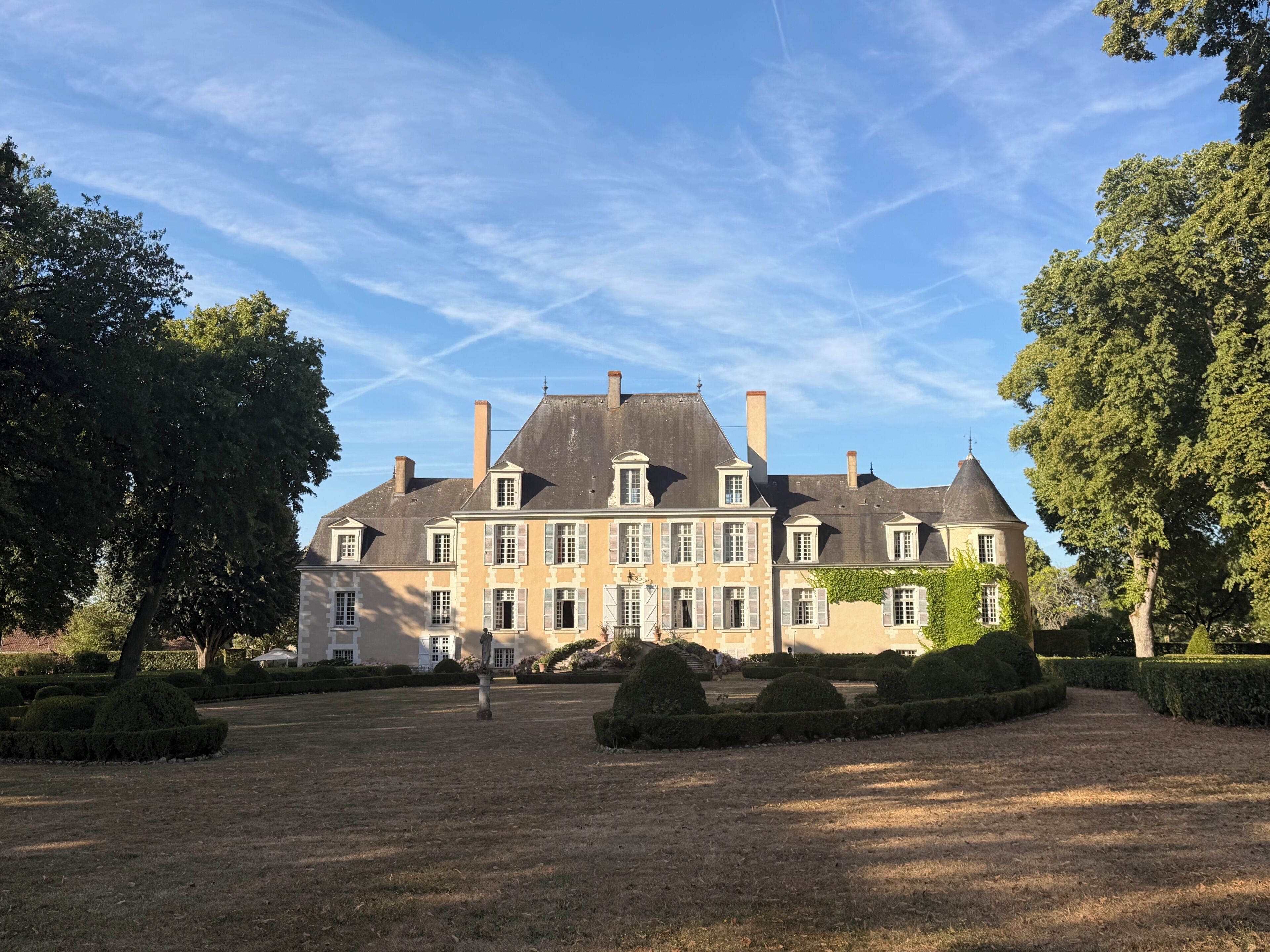 Un grand bâtiment historique à l’architecture symétrique, doté d’une cour centrale et de jardins bien entretenus.
