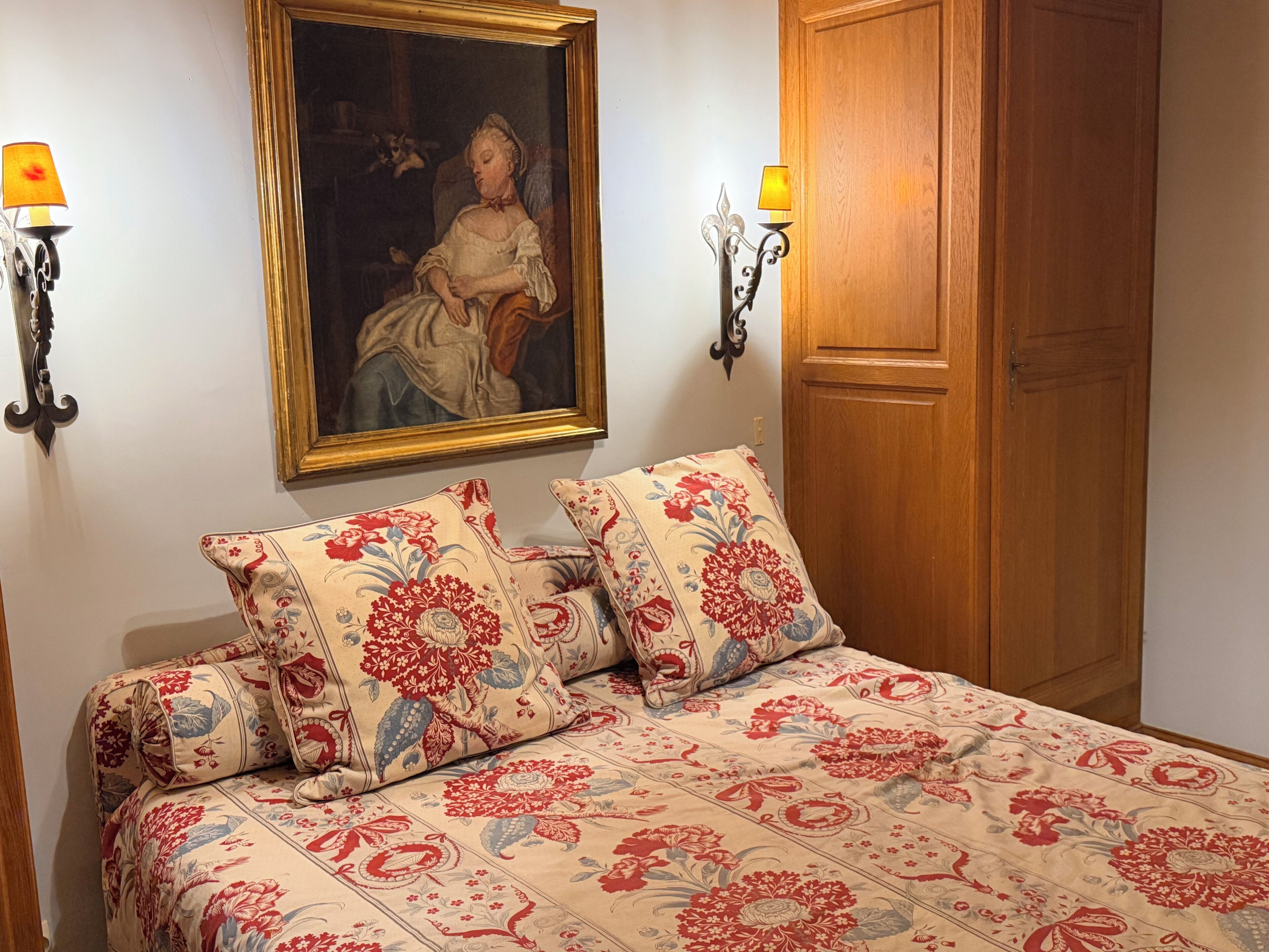 Une chambre à coucher avec un lit, un tableau et deux appliques murales.