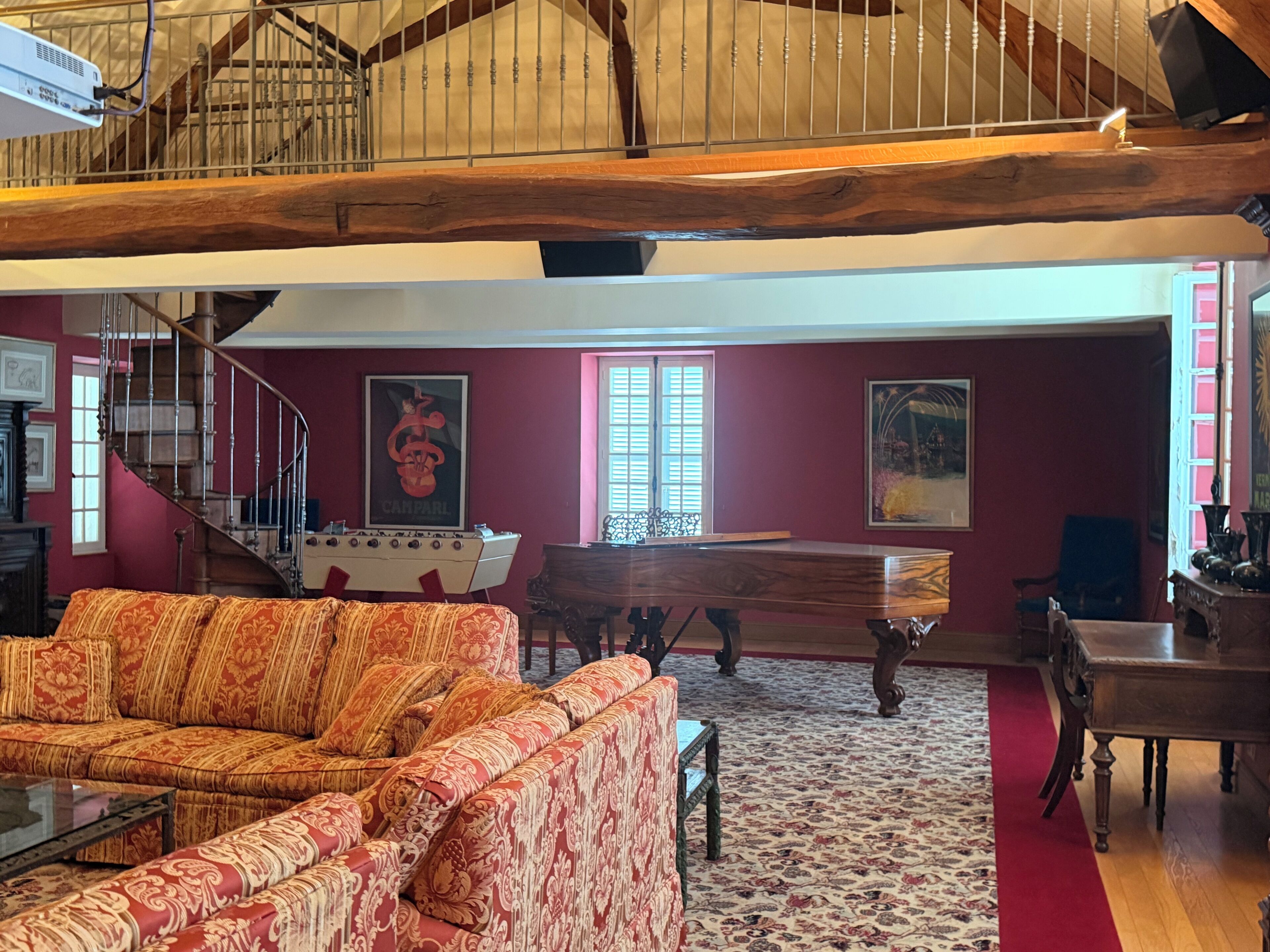 A spacious living room with a red sofa, a pool table, and a staircase leading to an upper level.
