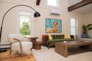 Ein Wohnzimmer mit einem grünen Sofa, einem weißen Sessel, einem Couchtisch und einem Bild von einem Fuchs.