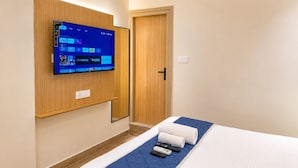 A hotel room with a bed, a TV mounted on the wall, and a door.