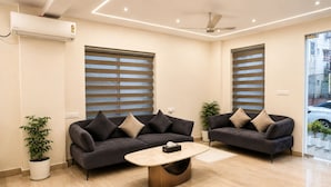 A modern living room with two sofas, a coffee table, and a ceiling fan.