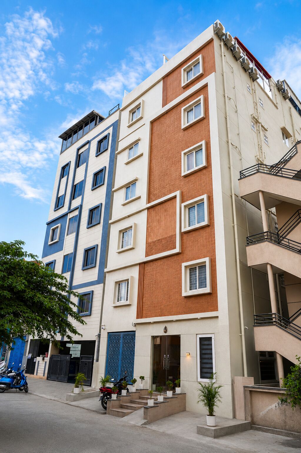 A multi-story residential building with a modern design, featuring a mix of window styles and a visible entrance with steps leading to the door.