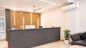 A reception desk with a nameplate, a ceiling fan, and a potted plant.